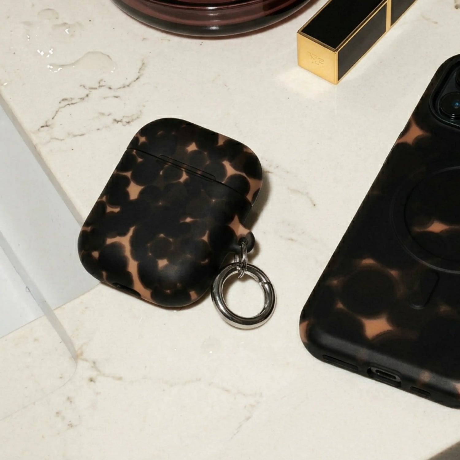 Phone case, air pod case, and lipstick on a marble surface