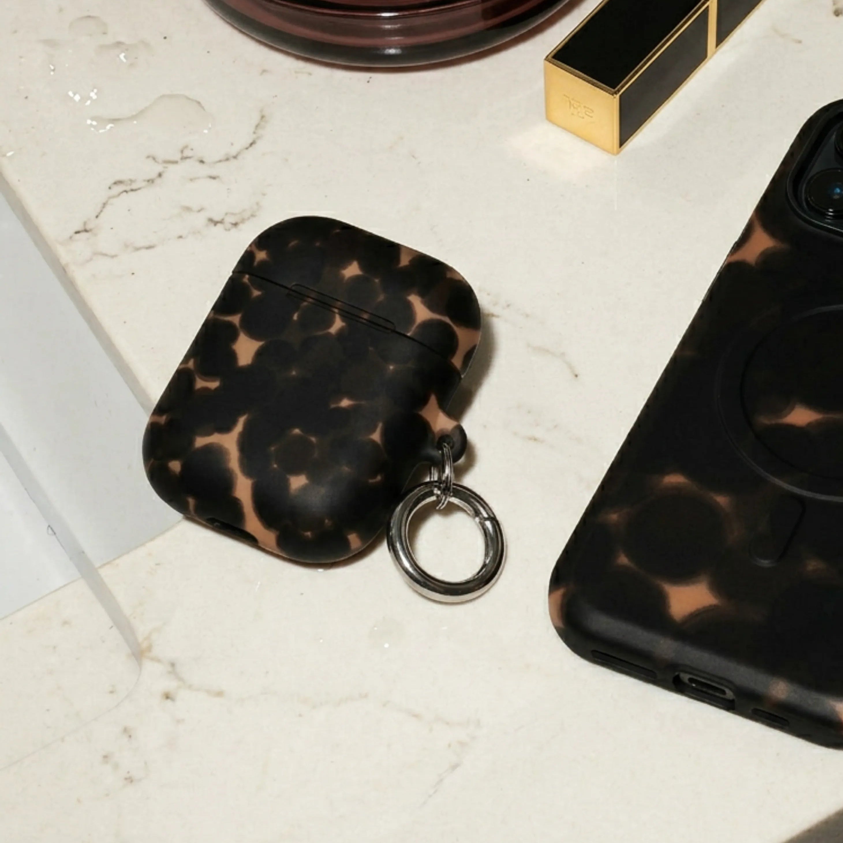 Phone case, air pod case, and lipstick on a marble surface